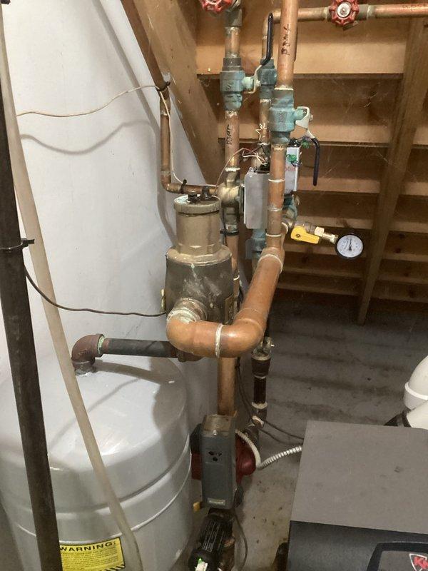 # No Heat Service Call - Lochinvar Boiler System

Responded to a no heat complaint for a Lochinvar boiler system located in a basement utility area. Upon arrival, conducted a thorough inspection of the heating system and associated components.

Examined the boiler installation including all copper piping, valves, and pressure controls. The system displayed significant age with visible patina on copper lines and oxidation present throughout the piping assembly. Inspected the Caleffi valve assembly, which showed green corrosion and white mineral deposits around joint connections - common indicators of long-term service and potential moisture exposure.

Evaluated multiple shut-off valves with red wheel handles mounted to the wooden framing above the system. Checked pressure gauge readings and verified all connection points, compression fittings, and solder joints for integrity. Assessed the electronic monitoring device with digital display to confirm system diagnostics were functioning pr
