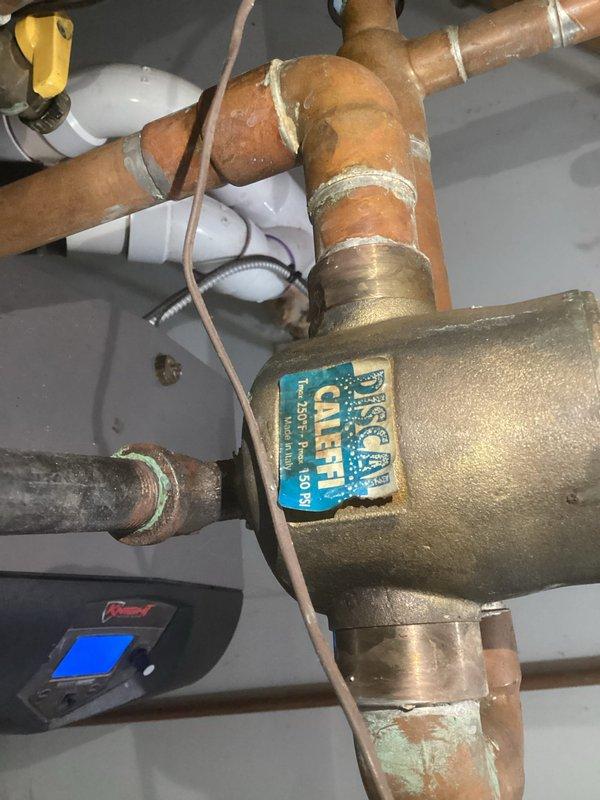 # No Heat Service Call - Lochinvar Boiler System

Responded to a no heat complaint for a Lochinvar boiler system located in a basement utility area. Upon arrival, conducted a thorough inspection of the heating system and associated components.

Examined the boiler installation including all copper piping, valves, and pressure controls. The system displayed significant age with visible patina on copper lines and oxidation present throughout the piping assembly. Inspected the Caleffi valve assembly, which showed green corrosion and white mineral deposits around joint connections - common indicators of long-term service and potential moisture exposure.

Evaluated multiple shut-off valves with red wheel handles mounted to the wooden framing above the system. Checked pressure gauge readings and verified all connection points, compression fittings, and solder joints for integrity. Assessed the electronic monitoring device with digital display to confirm system diagnostics were functioning pr