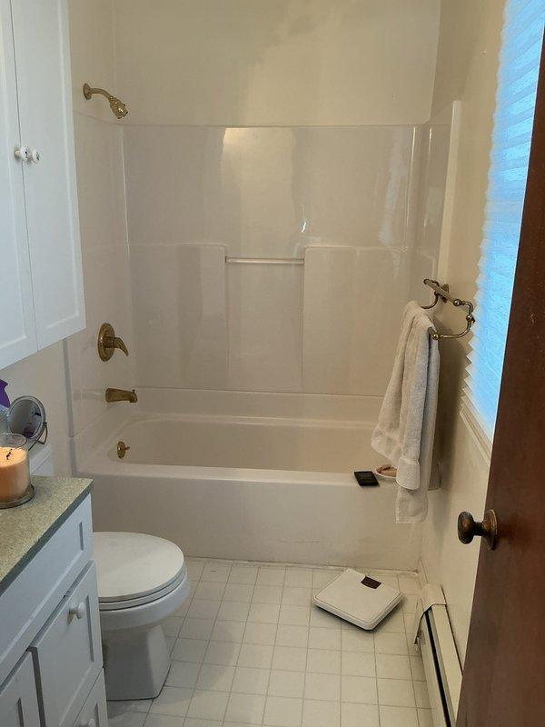 Conducted on-site assessment of upstairs bathroom for potential conversion to laundry room. Evaluated existing plumbing infrastructure including bathtub-shower combination unit with brass fixtures, toilet, and vanity with water supply and drain lines. Documented current bathroom layout and plumbing configuration to provide accurate quote for relocating water supply lines, drain connections, and venting required for washer and dryer installation.