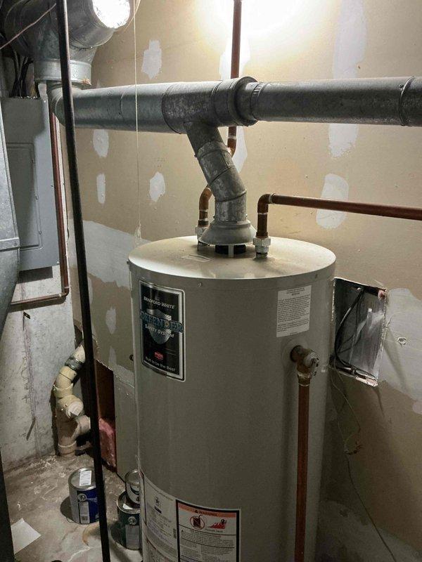 Performed on-site assessment of existing water heater requiring replacement in basement utility area. Evaluated current 40-gallon unit installation, documented all plumbing connections including galvanized and copper supply lines, PVC drainage system, and electrical requirements. Photographed equipment configuration and surrounding mechanical room infrastructure to provide accurate replacement estimate and ensure proper sizing for new unit installation.