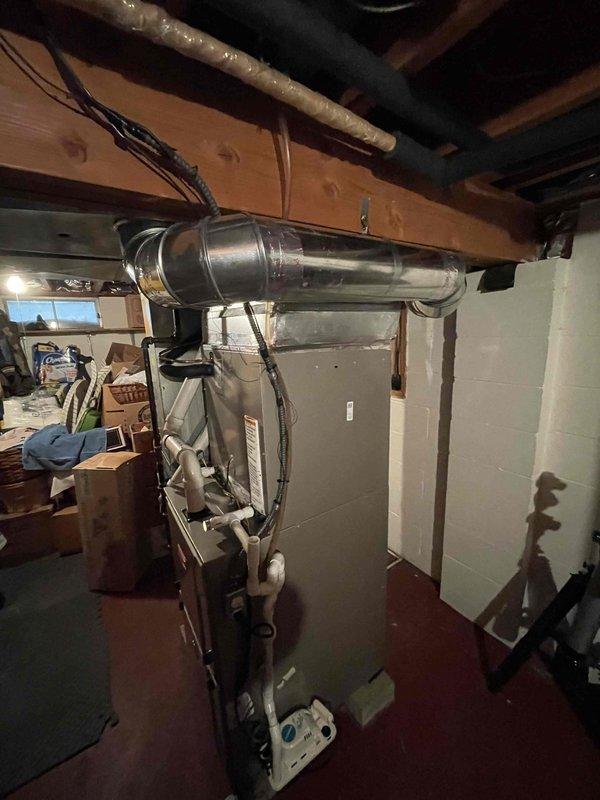 Completed full air conditioning system replacement in residential basement mechanical room. Installed new Bryant HVAC equipment including air handler unit and associated components. Ran and connected white PVC condensate drainage lines between units and routed to proper termination points. Installed refrigerant line set with copper piping, securing lines along ceiling joists to outdoor condensing unit. Mounted auxiliary equipment including humidifier or water treatment device on wall adjacent to main system. Connected all electrical wiring and control circuits to ensure proper system operation. Tested system startup, verified airflow through ductwork, and confirmed all safety controls functioning correctly. Left equipment operational and mechanical room secure.