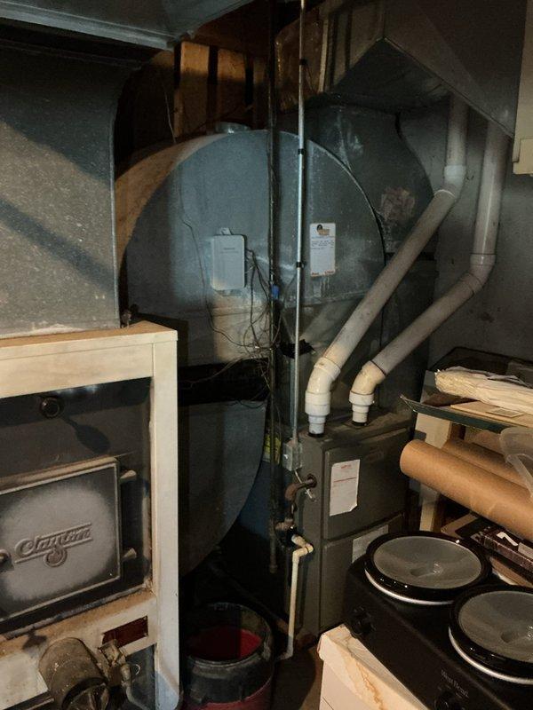 Conducted on-site evaluation of existing HVAC system for furnace and air conditioning replacement estimate. Assessed current heating setup including wood-burning stove and associated ductwork in mechanical room. Documented existing equipment configuration, venting systems, and spatial constraints for proposed system installation. Evaluated PVC drainage and venting infrastructure along with electrical components to determine compatibility requirements for new HVAC equipment.