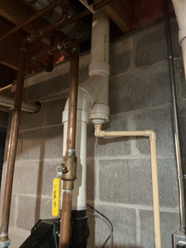 Provided estimate for water heater replacement in basement utility area. Assessed existing white cylindrical water heater with top-mounted circulator pump, copper supply piping, and electrical connections. Evaluated surrounding plumbing infrastructure including PVC drainage system, brass shutoff valves, and existing concrete floor conditions for new installation requirements.