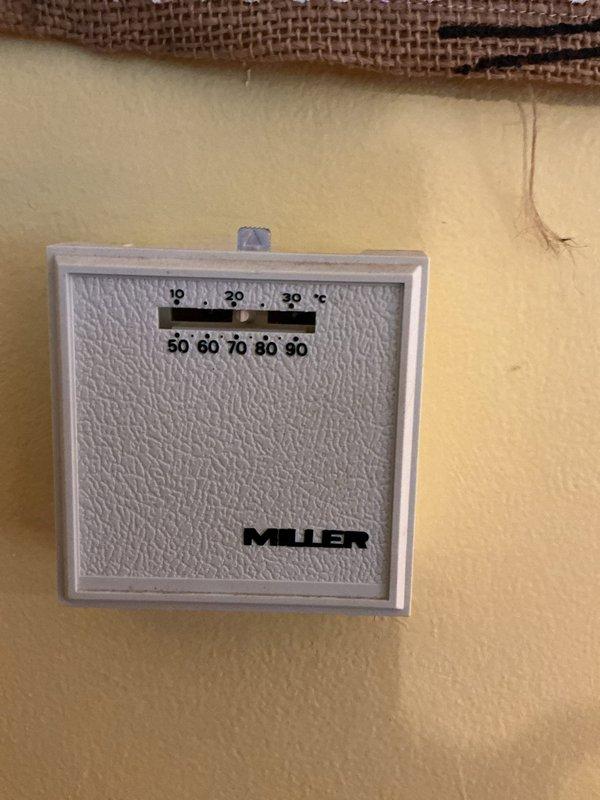 Conducted sales estimate for furnace replacement at residential property. Documented existing HVAC system located in vertical utility closet, including current furnace unit with gray metal casing and associated ductwork. Photographed existing Muller thermostat and complete equipment configuration to provide accurate replacement proposal.