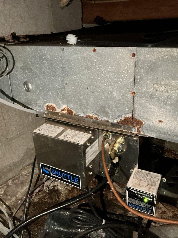 Conducted on-site evaluation for steam humidifier replacement on residential HVAC system. Assessed existing air handler unit showing significant surface condensation and moisture issues, with current humidistat control mounted on exterior. Documented equipment condition including exposed insulation requiring attention and existing drainage/venting configuration with PVC piping. Evaluated mechanical equipment installation in basement area, identifying aging infrastructure with moisture-related staining on surrounding walls and rust indicators. Photographed copper piping connections, electrical wiring, and overall system layout to provide comprehensive estimate for steam humidifier replacement and associated components.