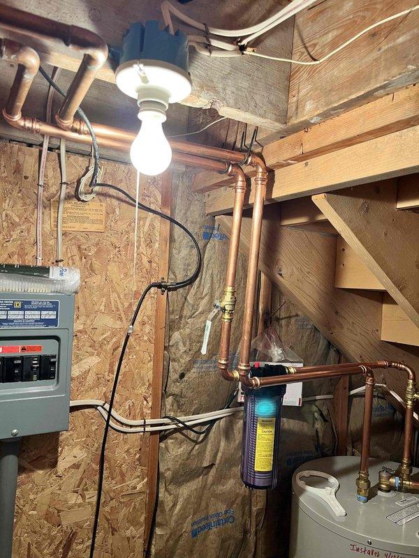 Installed 40-gallon residential water heater and whole house water filtration system in basement utility area. Repaired split copper pipe near water heater location. All plumbing connections completed with copper piping, appropriate valves and fittings installed per code, system tested and verified operational.