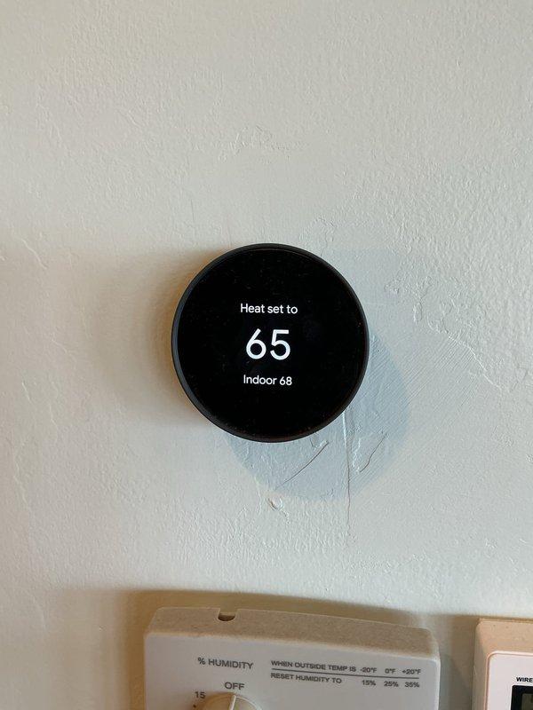 Conducted on-site evaluation for complete HVAC system replacement. Assessed existing outdated furnace and air conditioning equipment for replacement estimate. Documented current thermostat setup showing heat mode operational settings and evaluated exterior AC condenser unit location and accessibility for new equipment installation.