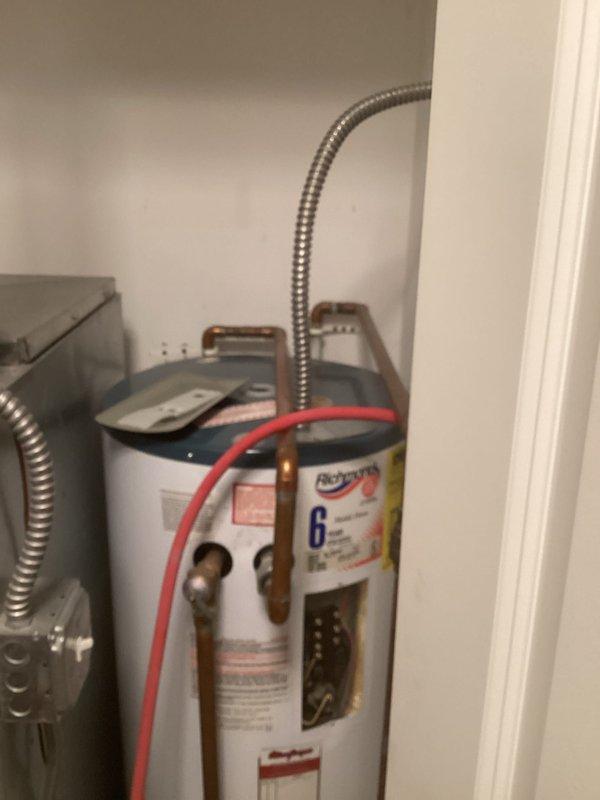 Responded to service call for water heater not reaching proper temperature. Upon arrival, inspected white cylindrical residential water heater located in utility closet alongside HVAC furnace system. Evaluated unit operation, checked temperature settings, and examined all supply lines, connections, and heating elements. Documented equipment condition with photos showing water heater installation with copper piping, brass fittings, flexible metal conduits, and red flexible hose connections at top of unit. Unit operational following service.