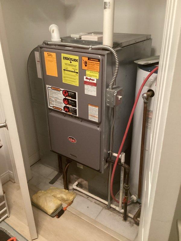 Responded to service call for water heater not reaching proper temperature. Upon arrival, inspected white cylindrical residential water heater located in utility closet alongside HVAC furnace system. Evaluated unit operation, checked temperature settings, and examined all supply lines, connections, and heating elements. Documented equipment condition with photos showing water heater installation with copper piping, brass fittings, flexible metal conduits, and red flexible hose connections at top of unit. Unit operational following service.