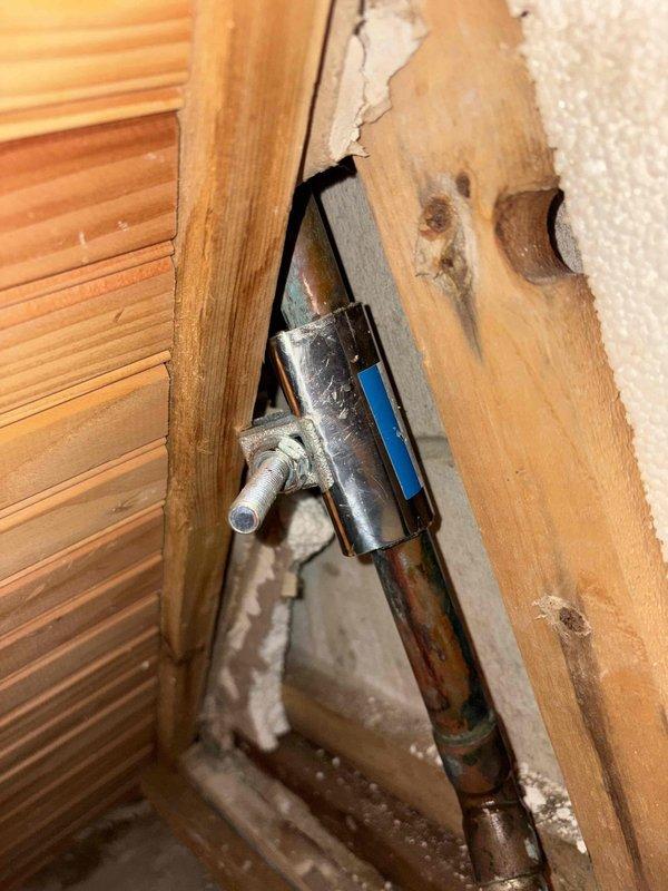 Responded to no hot water complaint caused by leak in radiant heating system. Located damaged section in crawl space where radiant heat line had developed a hole. Isolated the affected radiant heat zone by shutting off supply valves to restore domestic hot water functionality to the residence. Documented existing conditions with photos showing compromised piping and mounting hardware for future repair reference.