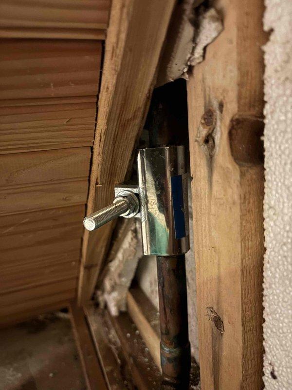 Responded to no hot water complaint caused by leak in radiant heating system. Located damaged section in crawl space where radiant heat line had developed a hole. Isolated the affected radiant heat zone by shutting off supply valves to restore domestic hot water functionality to the residence. Documented existing conditions with photos showing compromised piping and mounting hardware for future repair reference.
