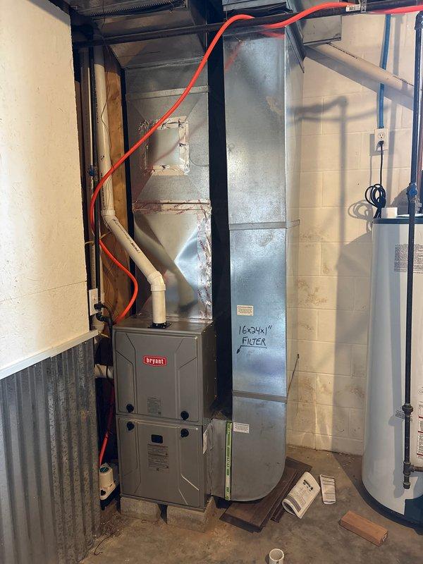 Completed removal and disposal of existing furnace unit from residential basement mechanical room. Installed new Bryant 2-stage furnace equipped with variable speed ECM blower motor for enhanced efficiency and comfort control. Positioned unit on wooden blocking for proper elevation and connected to existing ductwork system marked for 16x24x1 filter size. Verified all electrical connections, gas line routing via flexible conduit, and ductwork integration with water heater and auxiliary HVAC components. System tested and operational upon completion.