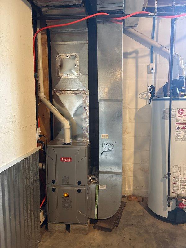 Completed removal and disposal of existing furnace unit from residential basement mechanical room. Installed new Bryant 2-stage furnace equipped with variable speed ECM blower motor for enhanced efficiency and comfort control. Positioned unit on wooden blocking for proper elevation and connected to existing ductwork system marked for 16x24x1 filter size. Verified all electrical connections, gas line routing via flexible conduit, and ductwork integration with water heater and auxiliary HVAC components. System tested and operational upon completion.