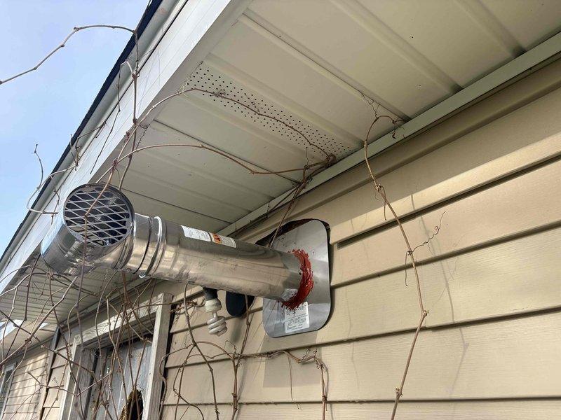 Responded to failed inspection for exterior exhaust vent installation where oversized wall penetration and improper siding placement caused gaps at termination point. Corrected previous fire caulking work by properly sealing the aluminum duct pipe connection and mounting plate to ensure code-compliant installation and prevent air infiltration around the exhaust vent assembly.