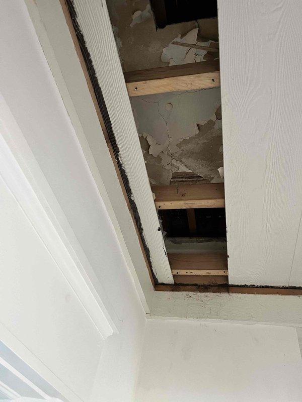 # Plumbing Leak Repair - Upstairs Exterior Wall

Responded to plumbing leak affecting upstairs exterior wall with water damage extending to under-stair area. Upon inspection, discovered active leak originating from copper supply line penetrating exterior wall assembly. Water infiltration had compromised drywall and plaster materials on underside of staircase, causing significant deterioration, peeling, and delamination of finished surfaces.

Accessed affected plumbing through basement/crawl space area where vertical copper supply line runs along foundation wall. Identified leak source at brass fitting connection on copper pipe approximately mid-height along the run. Shut off water supply to affected line and depressurized system.

Removed deteriorated brass fitting and inspected copper pipe for corrosion or damage. Pipe condition was satisfactory for repair. Cleaned pipe ends, applied flux, and installed new brass compression fitting with proper torque specifications. Pressure tested r