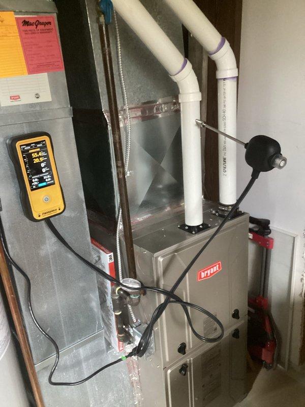 Responded to heating system safety concern regarding improper exhaust venting on 2019 Bryant furnace installation. County inspector identified that combustion exhaust gases were being discharged into the home's duct system rather than properly venting to the exterior. Performed combustion analysis testing which revealed 7 PPM CO in flue gases, 8.3% oxygen content, and 85.4°F stack temperature on natural gas high-efficiency system. Inspected PVC intake and exhaust venting configuration at furnace unit. Documented existing installation showing dual white PVC pipes extending from furnace top with improper connections allowing exhaust contamination of supply air. Corrected venting pathway to ensure combustion gases discharge safely outside the structure per manufacturer specifications and building code requirements. Verified proper system operation and confirmed no carbon monoxide present in living space after repairs completed.