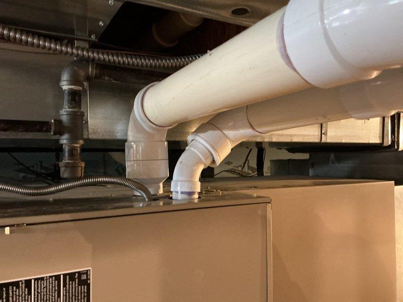 Completed on-site assessment for furnace and air conditioning system replacement estimate. Inspected existing HVAC equipment installation including ductwork, condensate drainage lines, flexible conduits, and electrical connections in mechanical space. Documented current system configuration with photographs showing equipment mounting, PVC drain piping, metallic flex lines, and associated plumbing components to develop comprehensive replacement proposal.