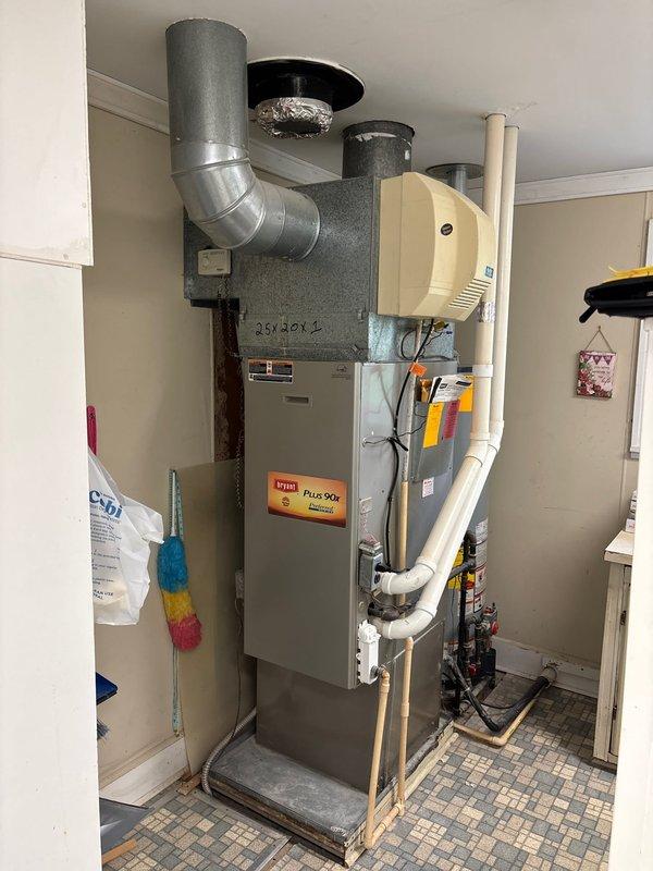 Conducted on-site evaluation of existing residential HVAC system to provide furnace replacement estimate. Inspected current gray furnace unit installed in utility closet, including assessment of ductwork connections, metal elbow transition to ceiling plenum, and overall system configuration. Documented existing equipment setup including mounted humidifier unit, white PVC venting pipes (Schedule 40 ASTM D1785 specification), and gas line connections at base of unit. Photographed current installation to capture system layout, clearances, and surrounding utility space constraints for accurate replacement planning and equipment sizing recommendations.