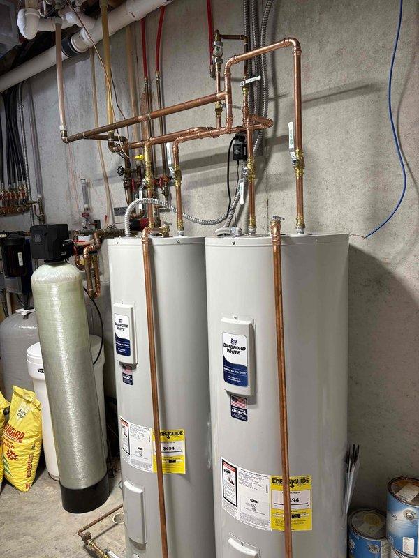 Installed two Bradford White electric water heaters in tandem configuration in utility room. Established complete copper piping network with manifold system featuring three-zone distribution valves for efficient hot water delivery throughout the residence. Connected units to existing water softener system using flexible stainless steel connectors and installed all required shut-off valves, pressure relief components, and electrical connections per manufacturer specifications and local code requirements.