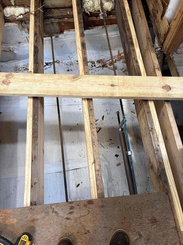 Assessed existing hydronic heating system for potential removal of baseboard heating in one room. Inspected dual circulation pump configuration with red and green circulators connected via copper piping with isolation valves, documenting current system layout and zone control setup. Evaluated floor joist access points and examined structural considerations for baseboard removal and potential pipe modifications in the affected area.