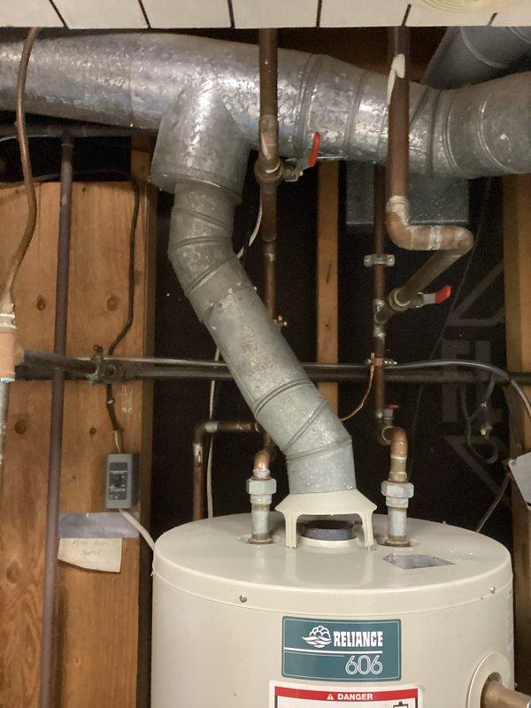 Responded to no hot water complaint on a 23-year-old Reliance 606 residential water heater. Upon inspection, determined the unit had reached the end of its serviceable life based on age and condition. Documented existing installation showing water heater in basement utility area with standard copper supply piping, brass fittings, red-handled shut-off valves, and proper venting configuration with flexible duct. Unit was connected to water softener system with PVC and flexible supply lines at base. Photographed the installation for customer records showing all connections, labels, and surrounding mechanical equipment. Advised customer of replacement options given the advanced age of the appliance, as water heaters typically have a 10-15 year lifespan and this unit was well beyond manufacturer's expected service life.