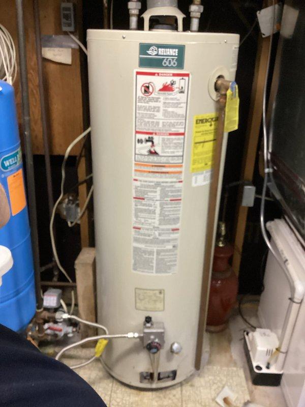 Responded to no hot water complaint on a 23-year-old Reliance 606 residential water heater. Upon inspection, determined the unit had reached the end of its serviceable life based on age and condition. Documented existing installation showing water heater in basement utility area with standard copper supply piping, brass fittings, red-handled shut-off valves, and proper venting configuration with flexible duct. Unit was connected to water softener system with PVC and flexible supply lines at base. Photographed the installation for customer records showing all connections, labels, and surrounding mechanical equipment. Advised customer of replacement options given the advanced age of the appliance, as water heaters typically have a 10-15 year lifespan and this unit was well beyond manufacturer's expected service life.