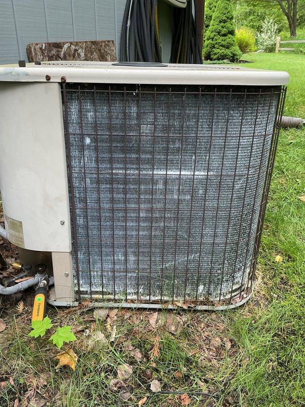 Completed annual cooling maintenance on 20-year-old Amana air conditioning system. Performed comprehensive tune-up including inspection of outdoor condensing unit, verified proper operation of all components, and documented equipment condition with photos showing unit positioned against building exterior with accumulated debris at base and normal weathering consistent with age.