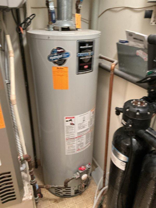 Performed water heater replacement estimate for a 20-year-old HydroJet residential unit that was no longer functioning correctly. Documented existing equipment configuration including copper supply piping, shut-off valves, and proximity to HVAC system and water softener in utility room. Photographed current installation to provide comprehensive assessment for replacement recommendations.