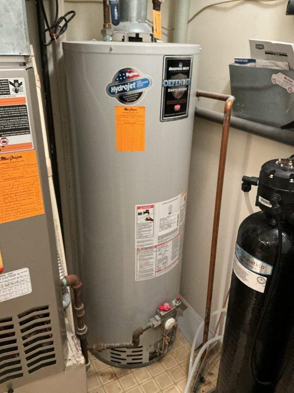 Performed water heater replacement estimate for a 20-year-old HydroJet residential unit that was no longer functioning correctly. Documented existing equipment configuration including copper supply piping, shut-off valves, and proximity to HVAC system and water softener in utility room. Photographed current installation to provide comprehensive assessment for replacement recommendations.