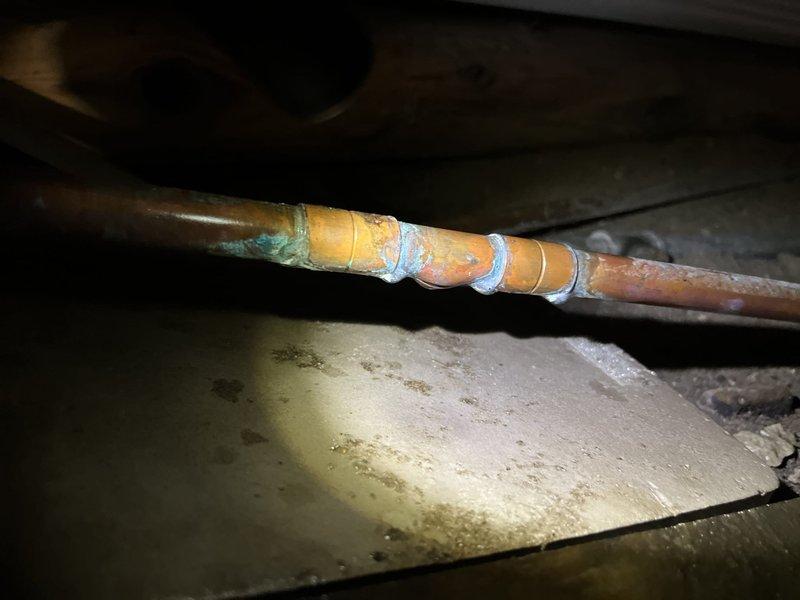 Responded to no-water emergency call due to pipe break in crawl space. Located failed section of copper water line with active leak causing service interruption. Temporarily repaired compromised pipe section with multiple layers of professional-grade repair tape to restore water service. Inspected surrounding copper piping system, noting age-related corrosion, patina buildup, and oxidation on pipes and compression fittings throughout the area. Documented existing conditions including greenish discoloration on copper components and general system deterioration. Restoration of water service confirmed upon completion of emergency repair.