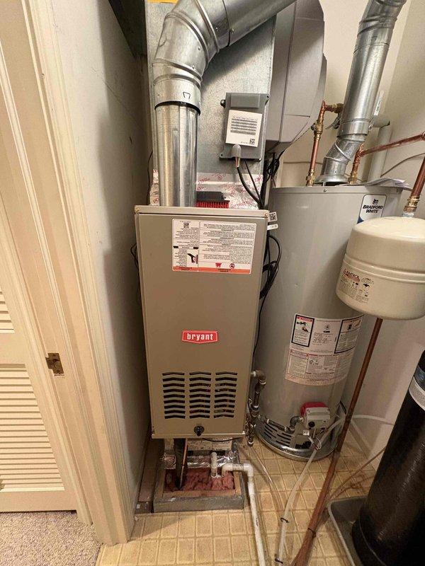 Completed full installation of Bryant furnace system, Puron Advance air conditioning unit, and water heater at residential property. Interior furnace installed in utility closet with proper ventilation ductwork including 90-degree elbow configuration, exterior AC unit positioned on gravel pad with electrical disconnect mounted to exterior wall, and water heater installed with copper piping connections. All equipment properly labeled, vented, and tested for operation with standard residential HVAC installation practices followed throughout.