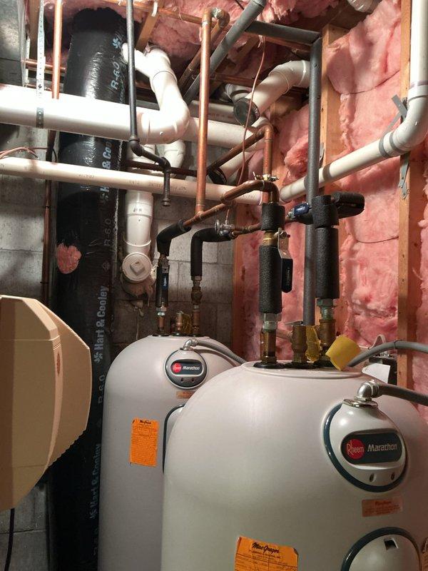 Responded to water heater leak originating from top connections causing water damage to basement floor. Upon inspection, identified compromised pipe fittings and connections above dual Marathon water heater installation. Assessed plumbing configuration including copper, PVC, and metal piping network with multiple junction points and shut-off valves. Documented moisture damage on concrete floor and evaluated overall system integrity to determine source of active leak and recommend appropriate repairs.
