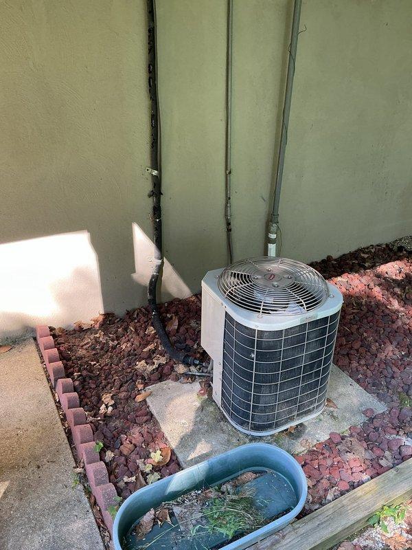 Conducted sales estimate for 2-ton air conditioning system replacement. Evaluated existing outdoor cylindrical condenser unit with silver metallic finish located in side yard on concrete pad, noting existing electrical and refrigerant line conduits running along exterior wall. Inspected indoor air handler unit installed in attic space, assessing copper refrigerant lines, existing ductwork connections, and electrical wiring. Documented current system configuration and provided replacement options for complete HVAC system upgrade.