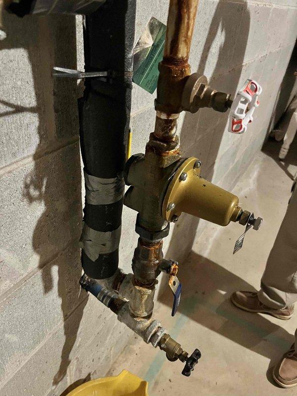 Responded to customer complaint of plumbing noise in basement pipes. Upon inspection, identified water hammer issue in the exposed piping assembly mounted on the basement wall. The vertical black pipe system with multiple copper branch lines and brass valves showed signs of aging and lacked proper air chambers or water hammer arrestors. Inspected all visible connections, pressure relief valves, and gate valves throughout the assembly to ensure proper operation and identify the source of the noise. Advised customer on the cause of the water hammer condition and recommended installation of water hammer arrestors to eliminate the banging noise occurring when valves are closed quickly. All existing valves and fittings were found to be secure with no active leaks observed at time of service.