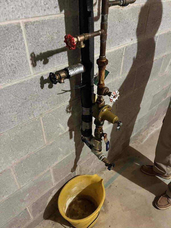 Responded to customer complaint of plumbing noise in basement pipes. Upon inspection, identified water hammer issue in the exposed piping assembly mounted on the basement wall. The vertical black pipe system with multiple copper branch lines and brass valves showed signs of aging and lacked proper air chambers or water hammer arrestors. Inspected all visible connections, pressure relief valves, and gate valves throughout the assembly to ensure proper operation and identify the source of the noise. Advised customer on the cause of the water hammer condition and recommended installation of water hammer arrestors to eliminate the banging noise occurring when valves are closed quickly. All existing valves and fittings were found to be secure with no active leaks observed at time of service.