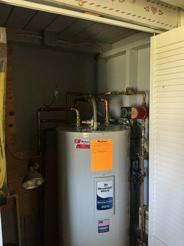 Installed Bradford White water heater in basement utility area with difficult access requiring two-person crew. Completed all copper piping connections, installed expansion tank, and ensured proper pressure relief valve configuration. Addressed customer questions regarding electrical grounding requirements following recent well installation.