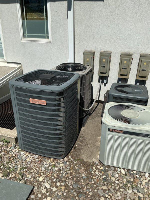 Conducted comprehensive site assessment of existing multi-unit HVAC system installation featuring multiple air conditioning condensers including Trane equipment positioned on exterior concrete pad. Documented current electrical infrastructure including disconnect boxes and circuit breaker panel schedule, photographed equipment configuration and electrical distribution setup to develop accurate replacement estimate for aging AC system.