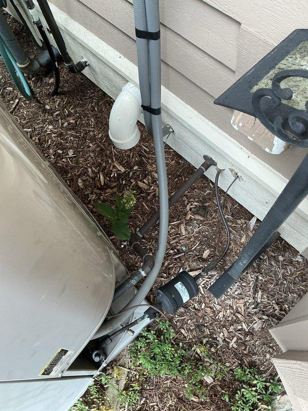 Completed on-site estimate for air conditioning system replacement. Documented existing Carrier HVAC equipment model CNPVP4824ACAABAA with specifications including 454 PSIG pressure rating, photographed exterior condensate drainage system with PVC piping and outdoor unit placement adjacent to building foundation.