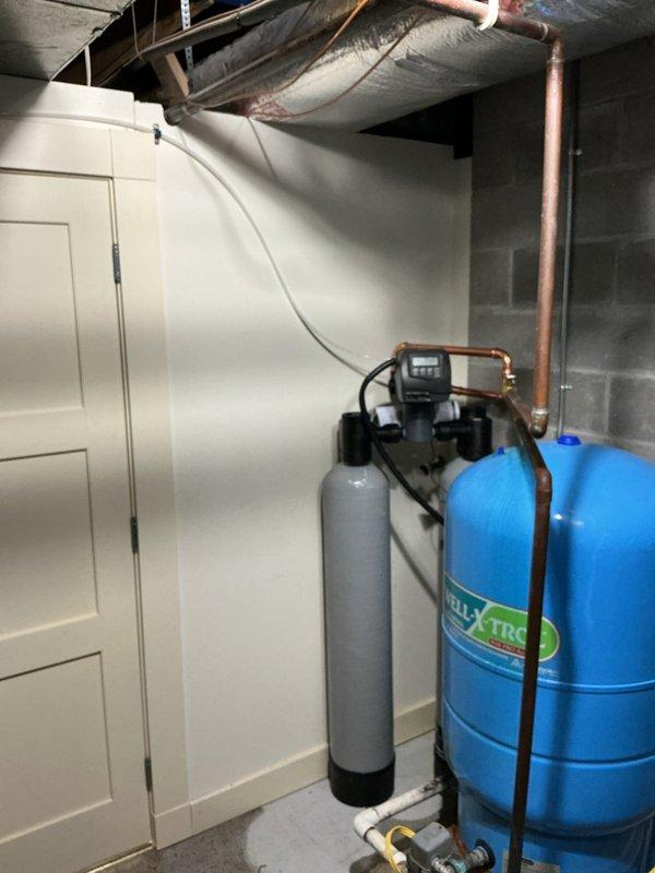 Removed and replaced non-functioning Culligan water softener system with new 2-cubic-foot Sterling water softener and carbon filter combination unit in basement utility room. Replaced deteriorated saddle valve with new valve during installation. Water testing confirmed hardness level of 17 grains per gallon with all other parameters within acceptable range. New carbon filter installed to improve water taste and odor while extending softener media lifespan. Connected all copper supply lines, installed blue Amtrol pressure tank, and verified proper operation of black control valve on softener unit. System tested and confirmed operational upon completion.