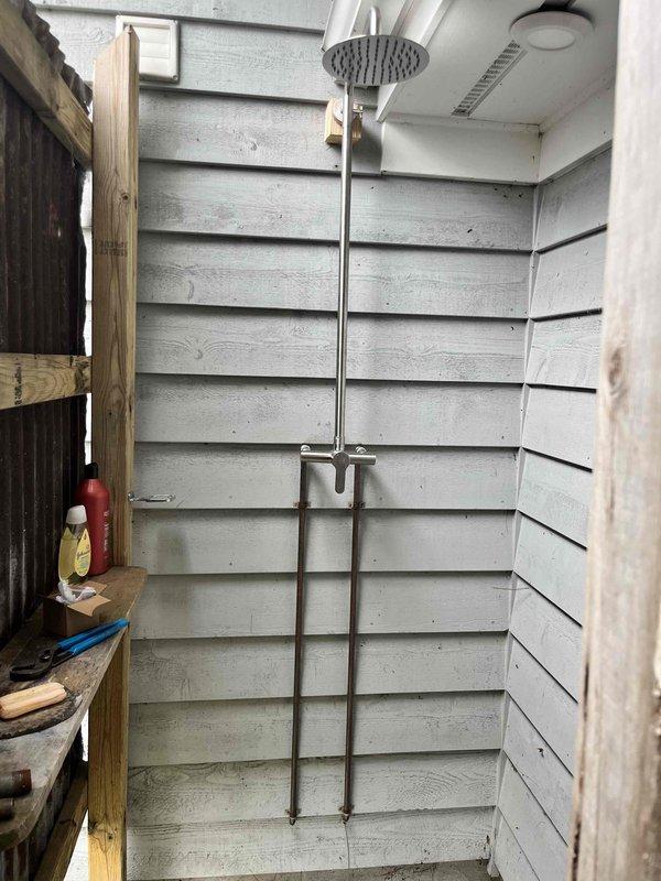 Corrected reversed hot and cold water supply lines from previous service call at outdoor shower installation. Verified proper water temperature delivery from both fixtures and tested functionality. Installed grab bar for safety and accessibility. All plumbing connections secured and tested for leaks with satisfactory results.