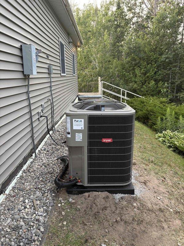 Completed removal and disposal of existing 2-ton air conditioning system including condenser unit and pad. Installed new Bryant HVAC system consisting of furnace with drain pan and 2-ton Puron condenser unit on concrete pad. New equipment positioned on exterior concrete pad with proper electrical disconnect and conduit installation, while furnace installed in mechanical room with PVC venting routed through ceiling and connected to existing ductwork.