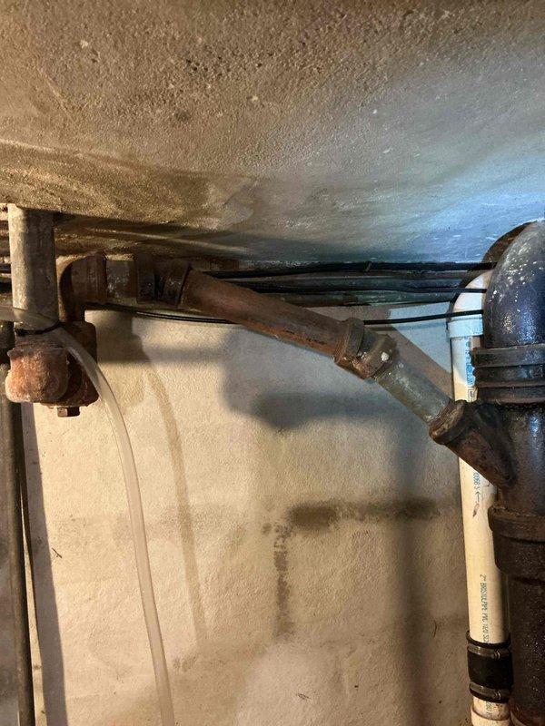 Conducted inspection of residential plumbing system to assess repairs needed for upstairs bathtub trap replacement, laundry sink hookup, and non-functioning faucet replacement. Photographed existing plumbing infrastructure including corroded pipes, aged fittings, and water heater connections showing significant oxidation and wear. Prepared documentation for quote preparation on requested plumbing repairs to support grant-funded home improvement project.