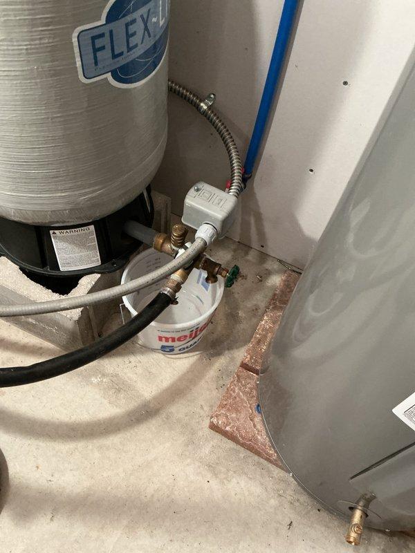 Conducted on-site assessment for whole-home water filtration or treatment system installation. Evaluated existing plumbing infrastructure including water heater connections, supply lines, and available installation space in utility area. Documented current system configuration with brass fittings, flexible supply lines, and PEX piping. Observed evidence of previous water staining on concrete floor near water heater base, indicating potential water quality concerns that support need for filtration system. Photographed existing plumbing layout and connection points to develop comprehensive quote for recommended water treatment solution.