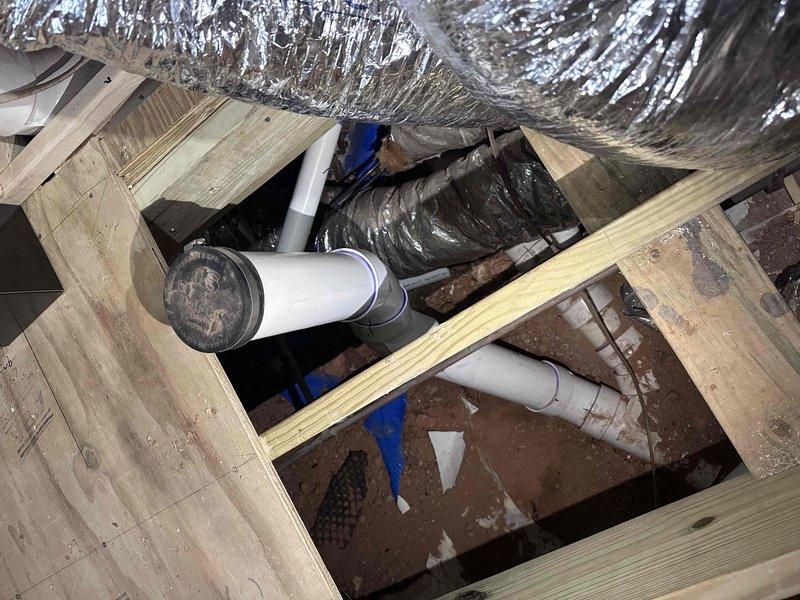 Completed follow-up inspection of plumbing installation project. Documented exposed wall section showing proper installation of black circular valve with copper and PVC connections. Additional documentation of underfloor/crawlspace area confirmed proper installation of drainage pipes, water supply lines, and HVAC ductwork running between floor joists. Completed follow-up inspection of plumbing installation project. Documented exposed wall section showing proper installation of black circular valve with copper and PVC connections. Additional documentation of underfloor/crawlspace area confirmed proper installation of drainage pipes, water supply lines, and HVAC ductwork running between floor joists.