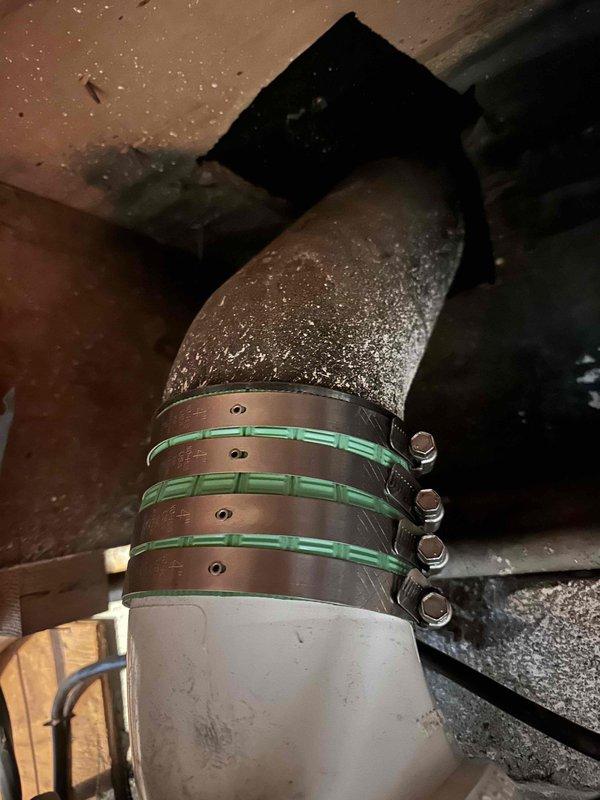 Inspected HVAC ductwork connection showing condensation issues at metal elbow joint secured with green-gasketed clamps. Examined exposed PVC plumbing pipe installation in ceiling/wall cavity with visible structural elements including damaged drywall and wood framing. Inspected HVAC ductwork connection showing condensation issues at metal elbow joint secured with green-gasketed clamps. Examined exposed PVC plumbing pipe installation in ceiling/wall cavity with visible structural elements including damaged drywall and wood framing.