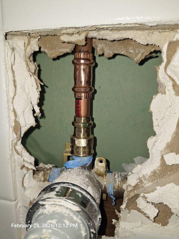 Identified source of bathroom ceiling leak as failed plumbing connection above. Opened wall to access vertical copper pipe assembly with compromised fitting. Observed water damage to surrounding drywall and backing material, with significant deterioration requiring repair after plumbing work is completed. Identified source of bathroom ceiling leak as failed plumbing connection above. Opened wall to access vertical copper pipe assembly with compromised fitting. Observed water damage to surrounding drywall and backing material, with significant deterioration requiring repair after plumbing work is completed.