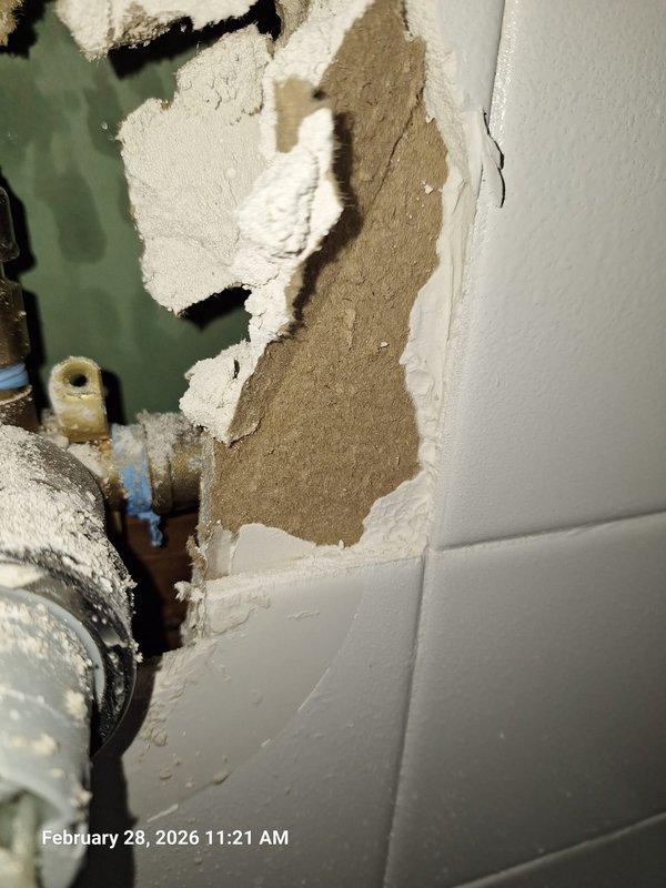 Identified source of bathroom ceiling leak as failed plumbing connection above. Opened wall to access vertical copper pipe assembly with compromised fitting. Observed water damage to surrounding drywall and backing material, with significant deterioration requiring repair after plumbing work is completed. Identified source of bathroom ceiling leak as failed plumbing connection above. Opened wall to access vertical copper pipe assembly with compromised fitting. Observed water damage to surrounding drywall and backing material, with significant deterioration requiring repair after plumbing work is completed.