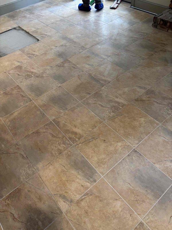 Performed site assessment for ceramic tile repair. Identified one missing floor tile in tan/beige tiled area near French doors. Documented existing flooring pattern and substrate condition for proper replacement material selection. Performed site assessment for ceramic tile repair. Identified one missing floor tile in tan/beige tiled area near French doors. Documented existing flooring pattern and substrate condition for proper replacement material selection.