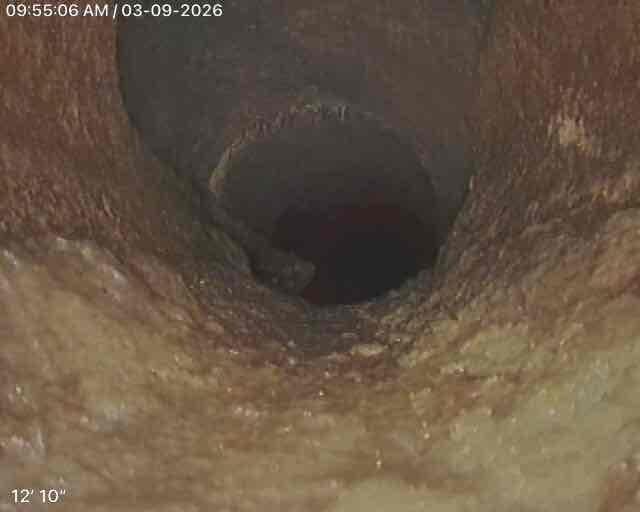 Conducted sewer scope inspection of main line, documenting conditions at approximately 12'10" depth. Observed significant rust and mineral buildup along the upper portions of the pipe with sediment accumulation along the bottom surface. Inspection revealed pipe narrowing with potential scaling issues, though flow appeared unobstructed at time of service. Conducted sewer scope inspection of main line, documenting conditions at approximately 12'10" depth. Observed significant rust and mineral buildup along the upper portions of the pipe with sediment accumulation along the bottom surface. Inspection revealed pipe narrowing with potential scaling issues, though flow appeared unobstructed at time of service.