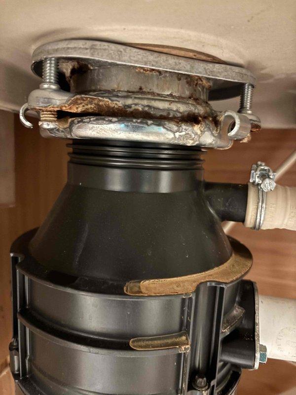 Responded to service call for kitchen sink leak suspected to be from garbage disposal. Inspection revealed significant corrosion and rust buildup at the disposal's mounting assembly and flange area. Water pressure was measured at approximately 75-80 PSI using a Watts gauge. Responded to service call for kitchen sink leak suspected to be from garbage disposal. Inspection revealed significant corrosion and rust buildup at the disposal's mounting assembly and flange area. Water pressure was measured at approximately 75-80 PSI using a Watts gauge.